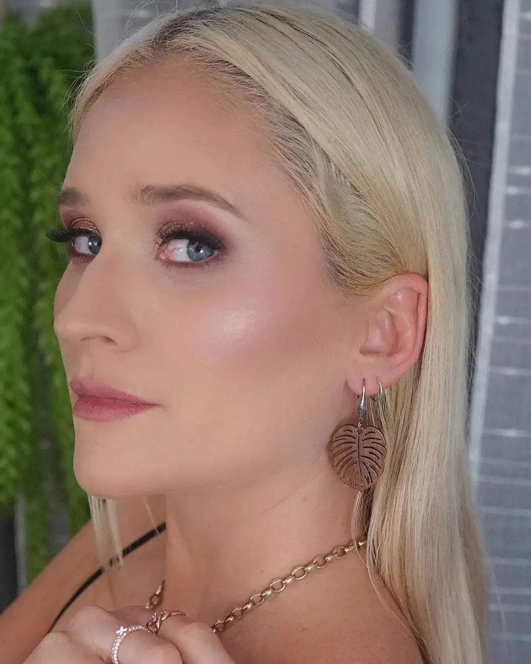 Blonde model wearing natural wood  monstera leaf earrings styled with black top
