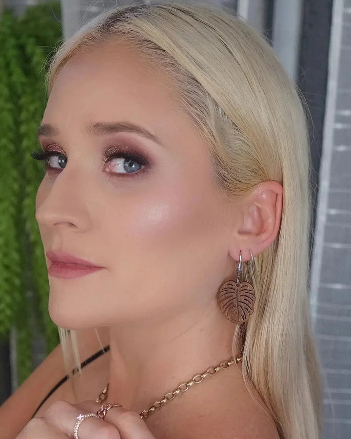 Blonde model wearing natural wood  monstera leaf earrings styled with black top
