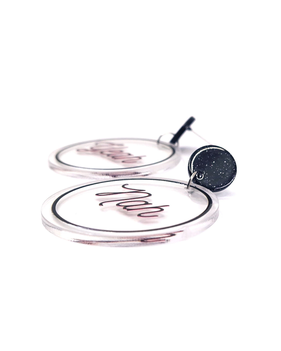 Close-up of Yeah Nah acrylic statement earrings with black script, clear round charms and glitter black studs.