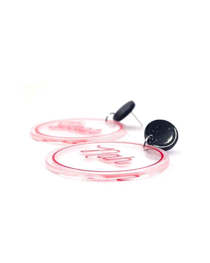 Close-up of Yeah Nah acrylic statement earrings with pink script, clear round charms and glitter black studs.