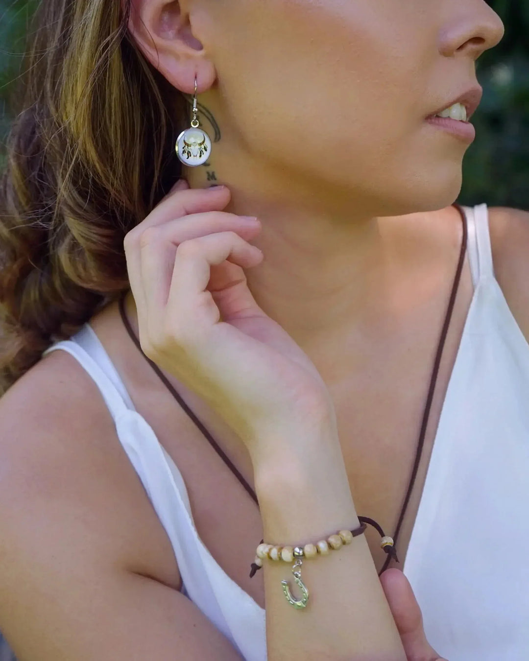 Woman wearing small round bull skull drop earrings with silver hooks