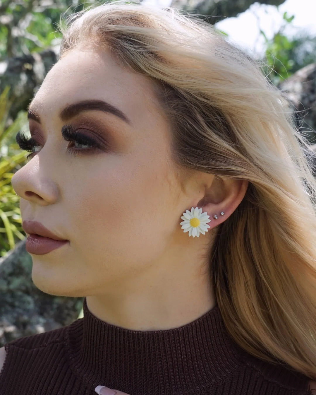Side view of model wearing white daisy stud earrings