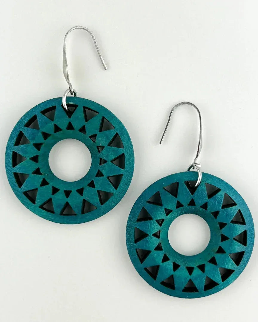 Close-up of dark teal timber earrings showing circular shape and detailed sunburst cut-outs