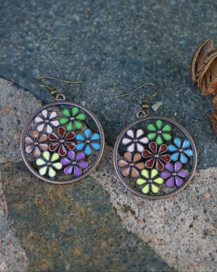 Close up of copper earrings showing the detailed lime, pink, and red enamel flower petals.