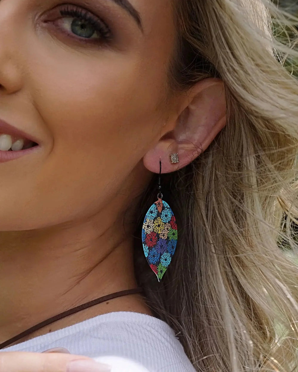 Colourful floral leaf drop earrings worn on ear showing long lightweight leaf shape