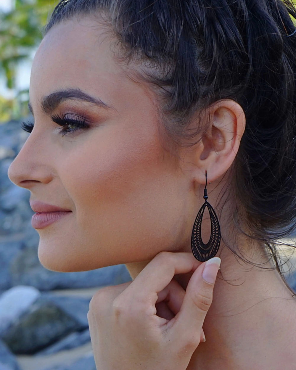 Model wearing black lace-cut teardrop dangle earring showing length and cut-out detail