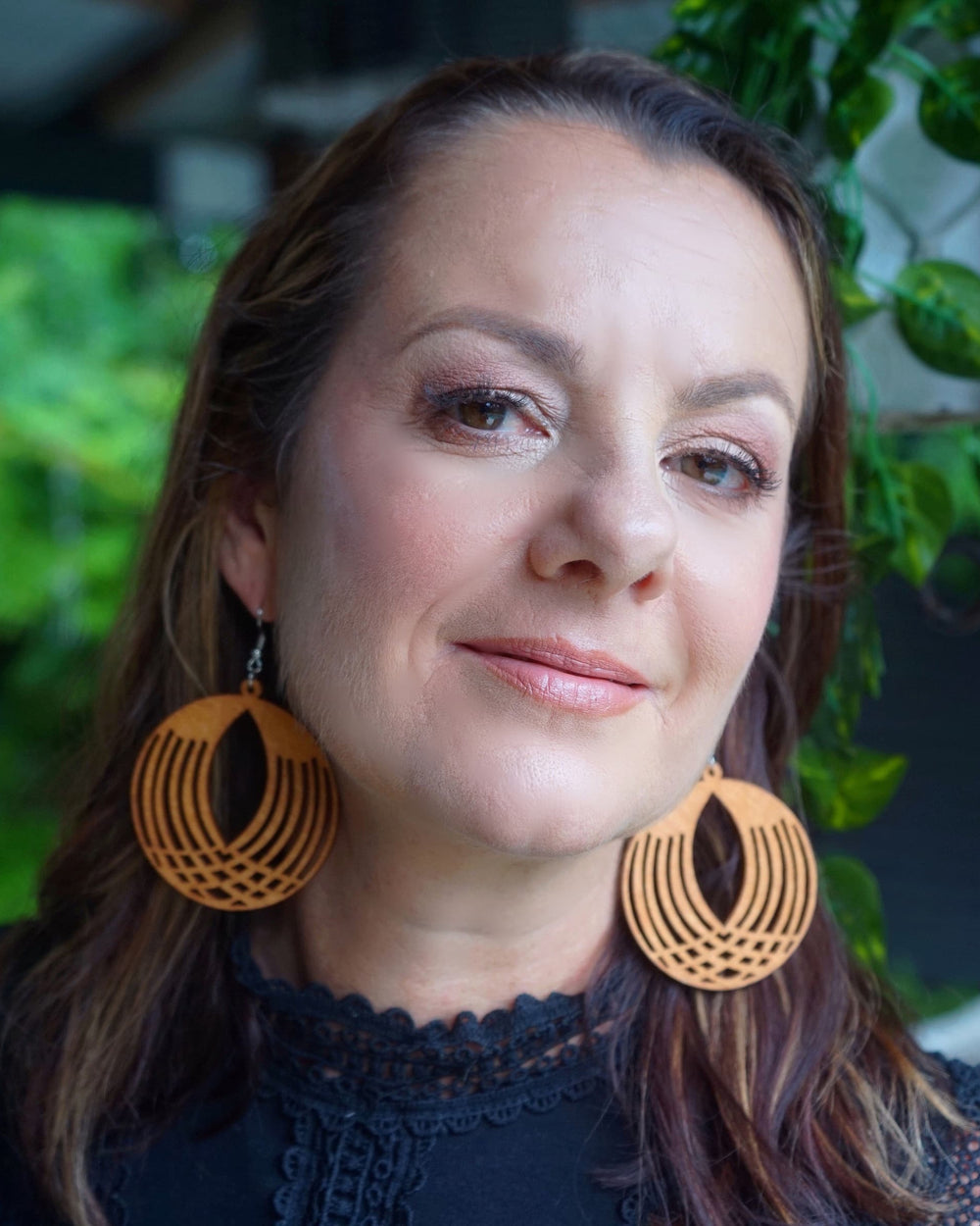 Model wearing large round geometrical timber drop earrings with cut-out pattern