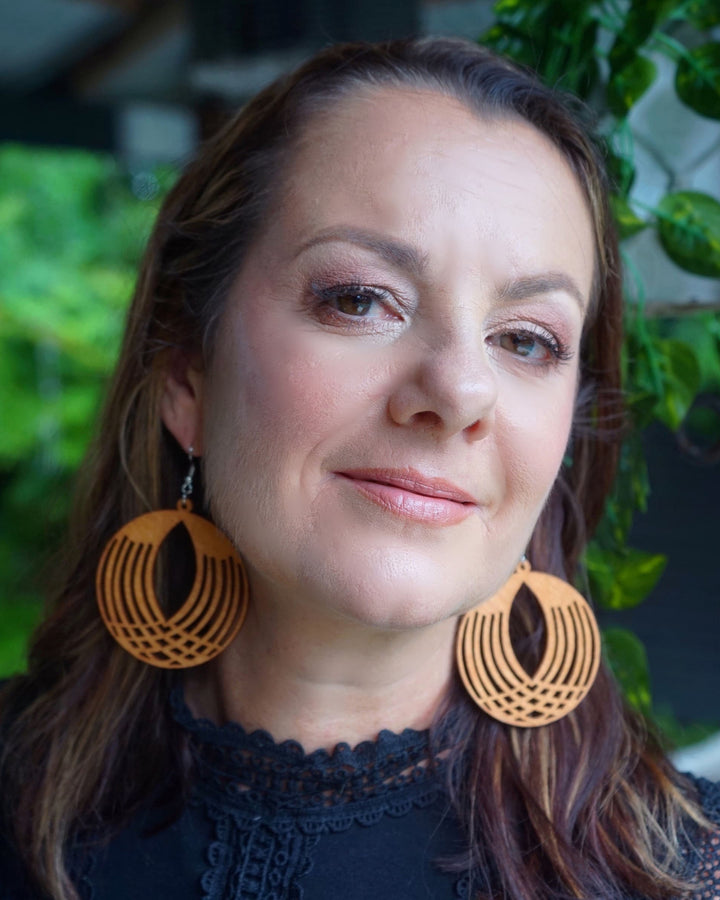 Model wearing large round geometrical timber drop earrings with cut-out pattern