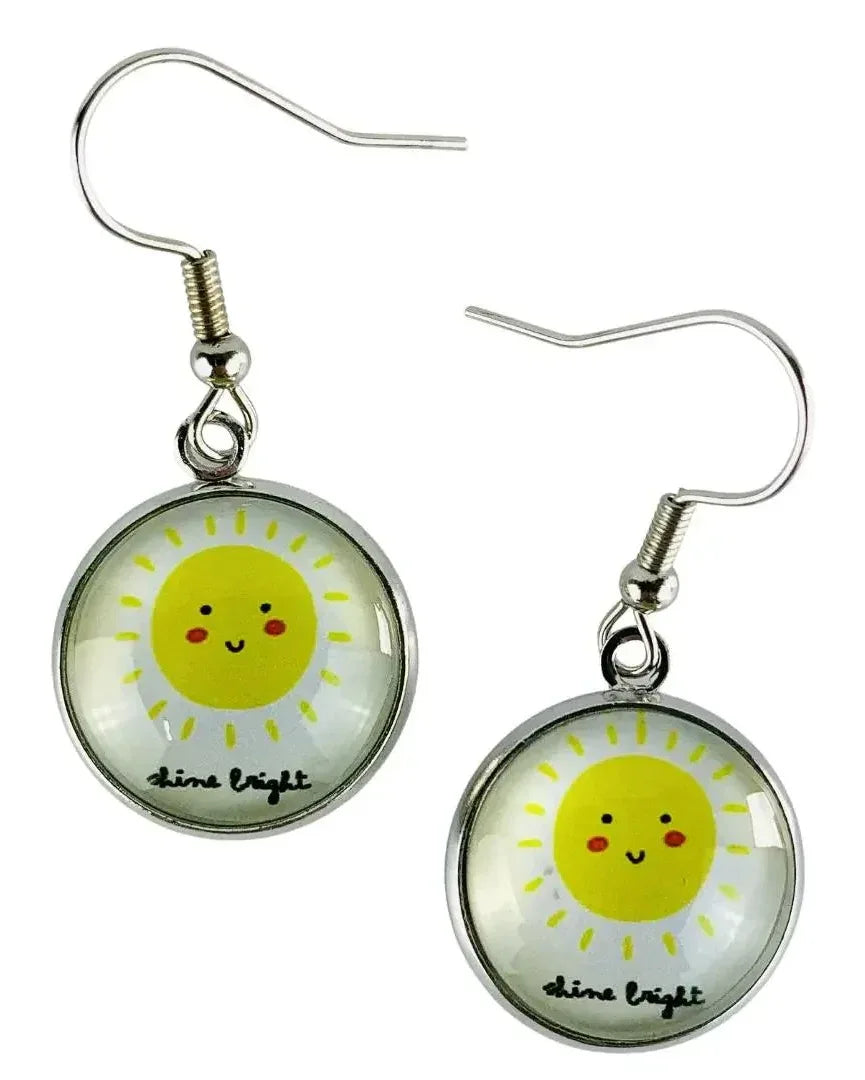 Yellow sun earrings with blushing cheeks and "Shine Bright" text under a glass dome.