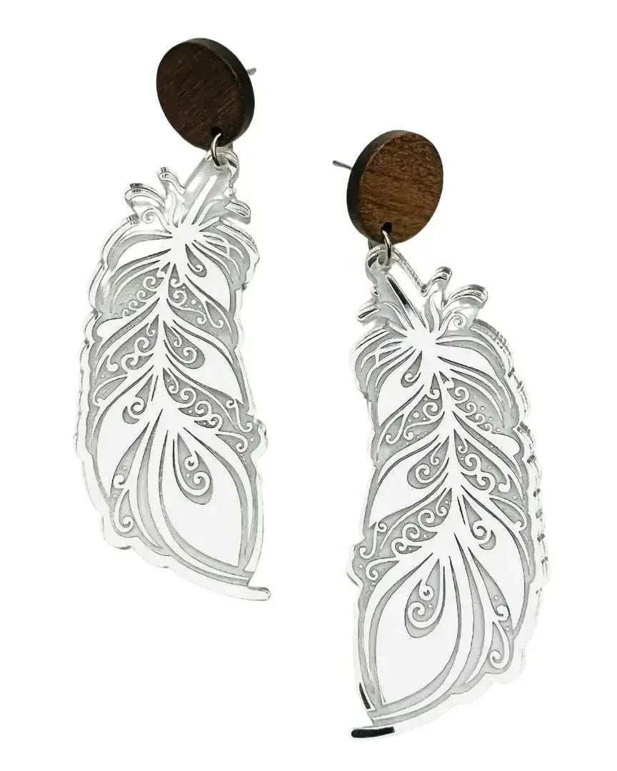 Close-up of silver feather drop earrings with round timber stud