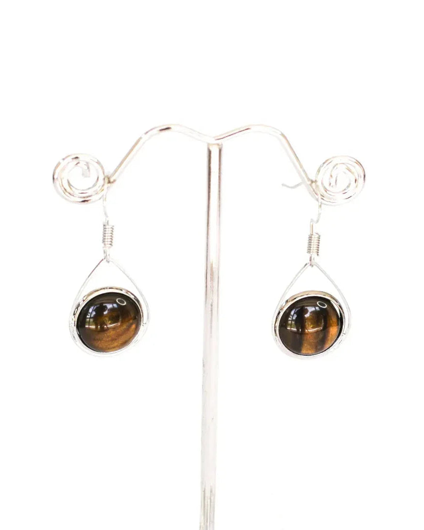 Tigers eye teardrop earrings hanging on a silver earring stand, showing the glossy domed glass