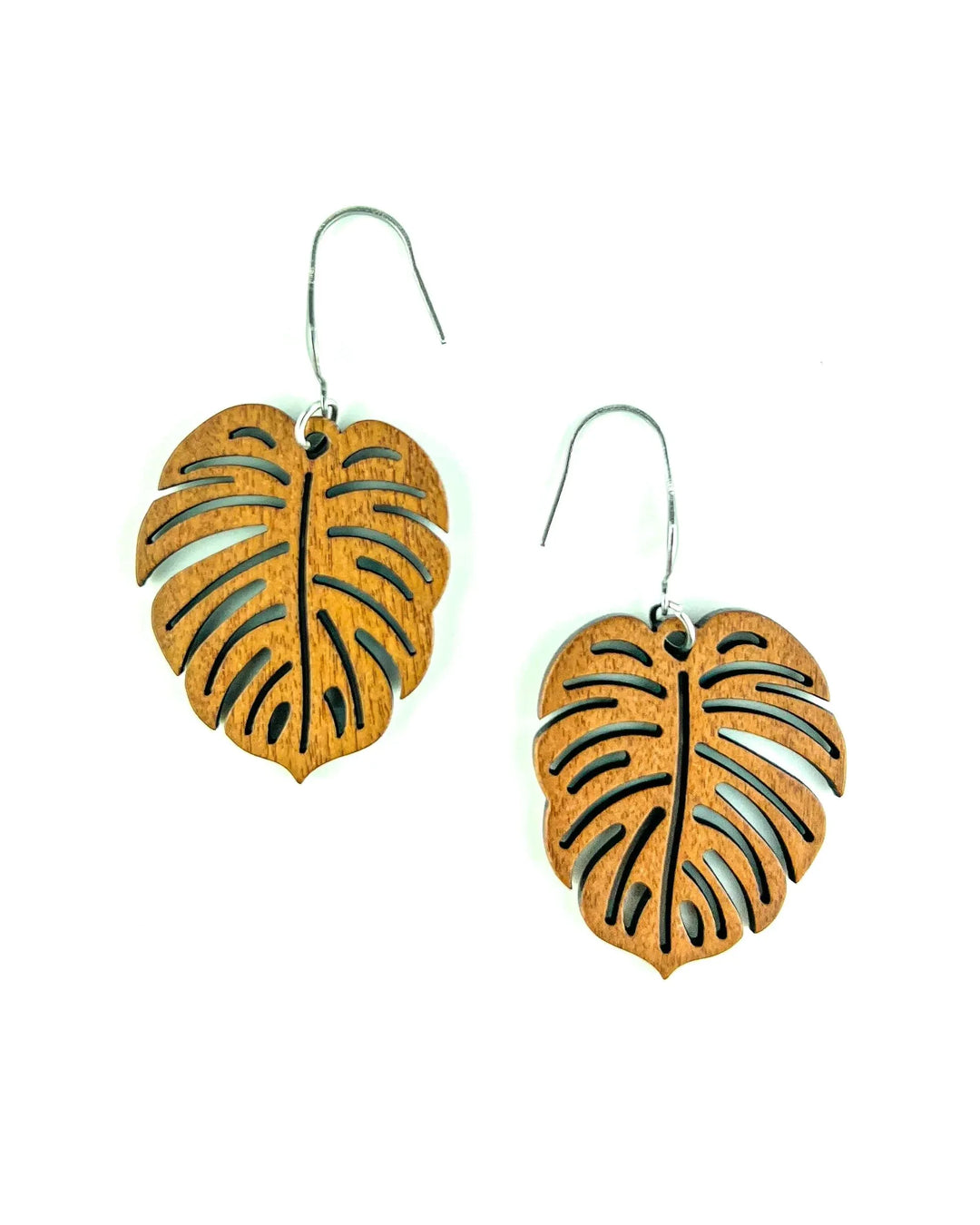 Close-up of natural timber monstera leaf drop earrings with cut-out vein details and silver hooks