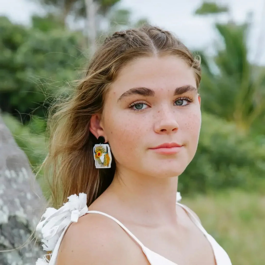 Model wearing western cow skull sunflower leopard print stud drop earrings with black round stud top